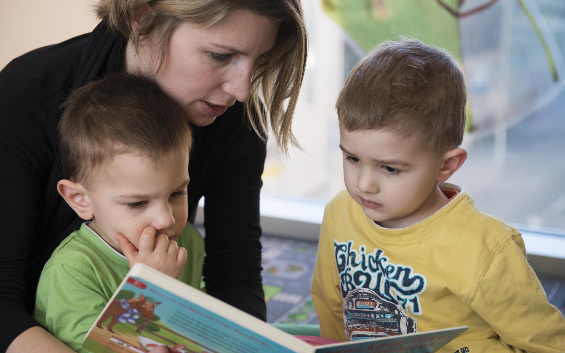 Frau liest zwei Kindern etwas vor