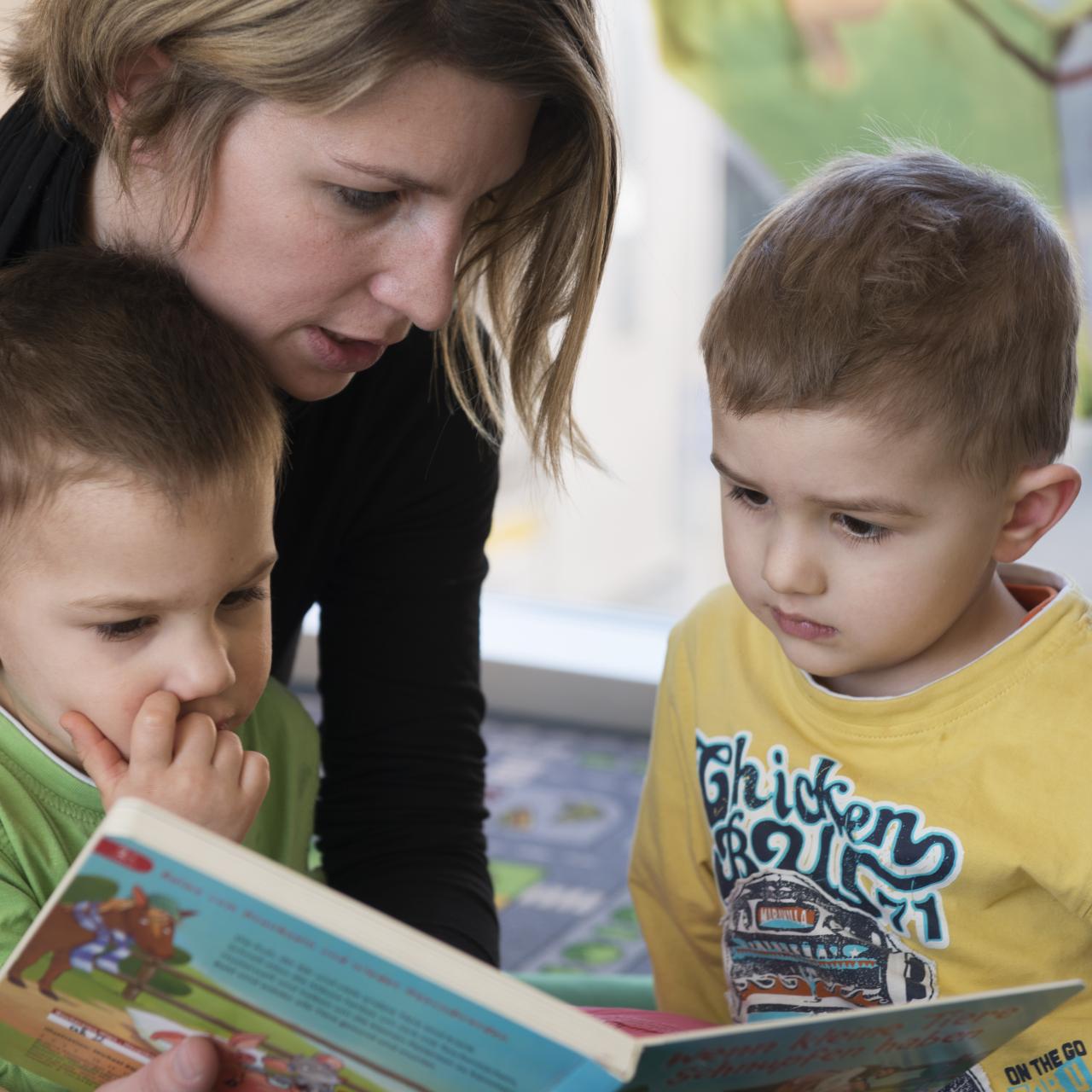 Frau liest zwei Kindern etwas vor